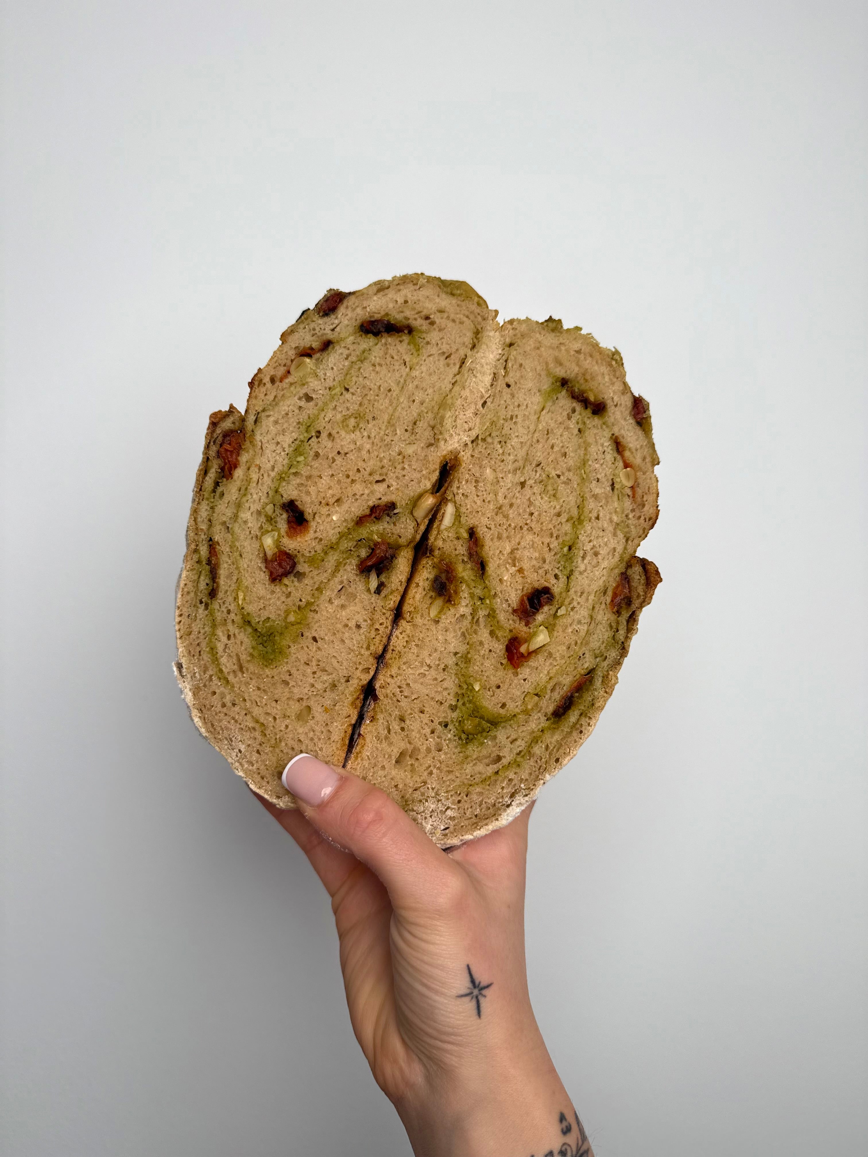 Sauerteigbrot mit grünem Pesto, Pinienkernen, getrockneten Tomaten und Parmesan